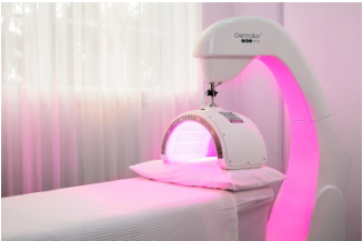 Professional LED light therapy machine emitting pink and red light over treatment bed in med spa